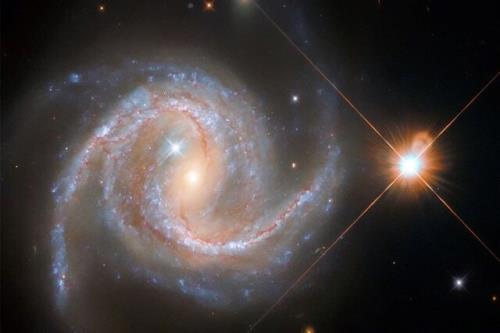 درخشش یک ستاره در کنار کهکشانی مارپیچی